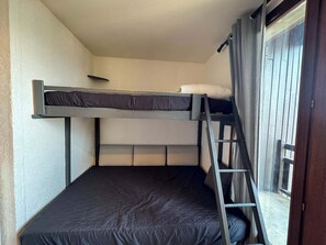 A bunk bed with a ladder, a window with curtains, and a door. - Studio 16m² - Balcon - Wifi - Risoul Le Villaret (Risoul)