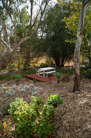 A wooden deck with a white bench surrounded by greenery and trees. - Donnybrook Cottages - Donnybrook (Clare)