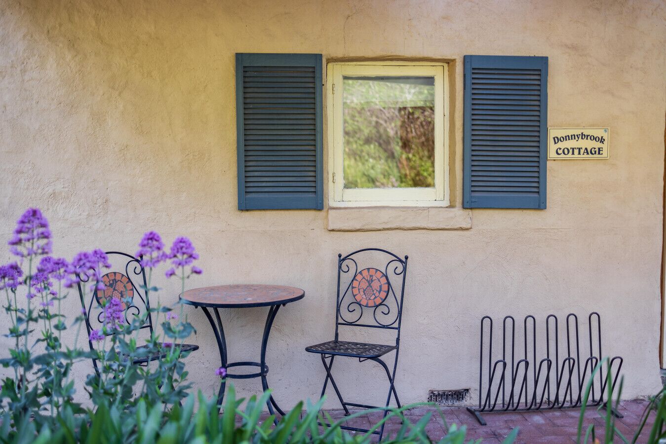 A cottage with a small window, two chairs, a table, and a sign reading 'Donnybrook Cottage.'