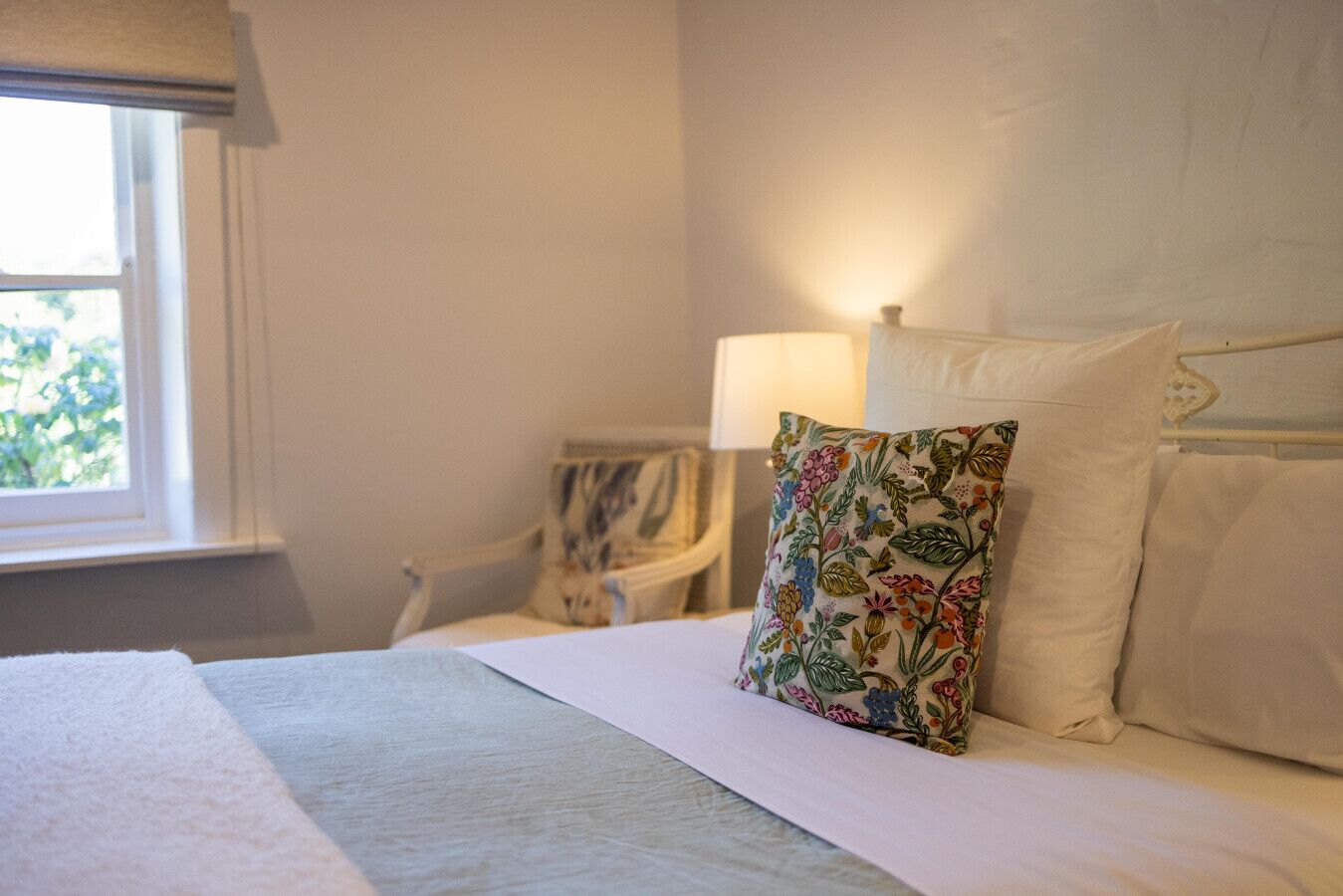 Una habitación de hotel con cama, mesita de noche, lámpara y ventana.
