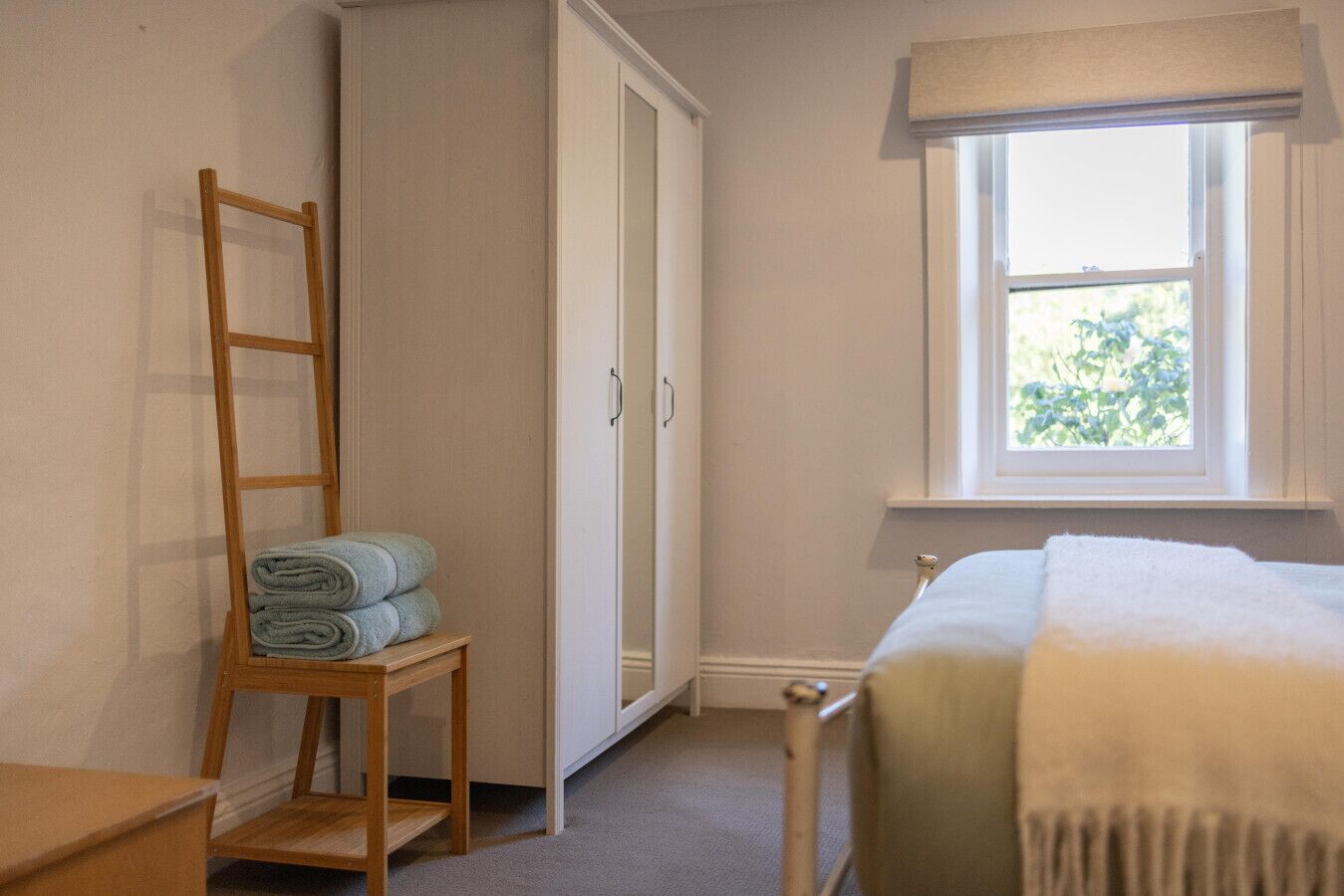 Un dormitorio con cama, ventana, armario y una escalera de madera.