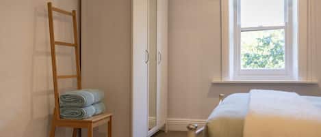 Un dormitorio con cama, ventana, armario y una escalera de madera.