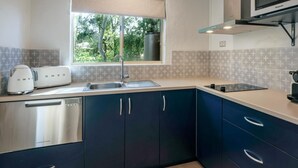 Une cuisine moderne équipée d’un lave-vaisselle intégré, d’un évier à deux bacs et d’un four à micro-ondes.