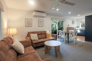 A living room with a sofa, a coffee table, and a dining area with chairs and a table.