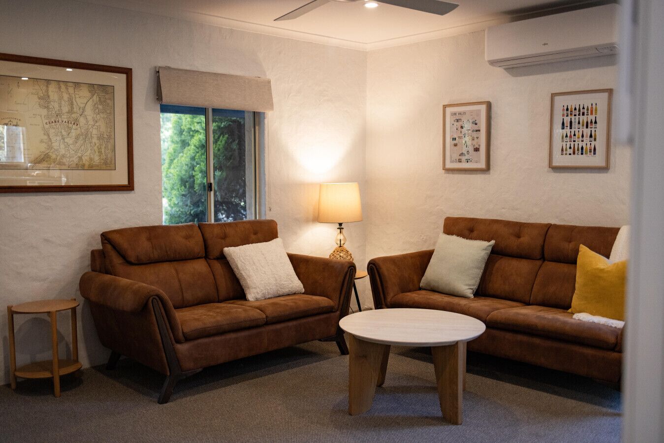 A living room with two brown sofas, a small round table, and a lamp.