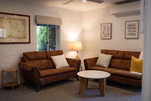 Ein Wohnzimmer mit zwei braunen Sofas, einem kleinen runden Tisch und einer Lampe.