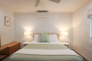 A hotel room with a bed, two bedside lamps, a small wooden bench, and an air conditioning unit on the ceiling. - Donnybrook Cottages - Hutt River (Clare)