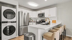 A modern kitchen with stainless steel appliances, a central island, and bar stools.