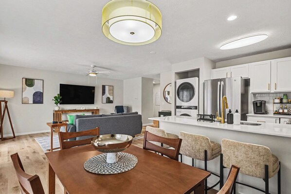 A modern kitchen with a central island, white cabinetry, and a built-in oven.