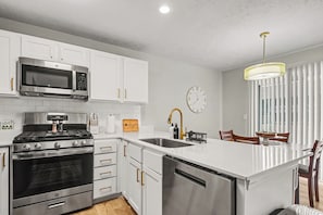 Una cocina moderna con electrodomésticos de acero inoxidable, armarios blancos y una isla central.