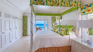 Een slaapkamer met een bed, een kaptafel en uitzicht op de oceaan.