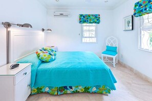 Un dormitorio con cama, una silla, una mesita de noche y una ventana con cortinas.