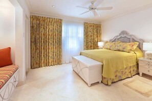 A bedroom with a bed, bedside tables, a bench, curtains, and a ceiling fan. - Stylish Beachfront Villa with Plunge Pool - Still Fathoms (3 bed) (Reeds Bay)