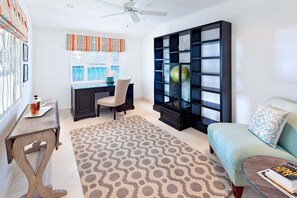 A room with a desk, chair, bookshelf, sofa, and a patterned rug. - Stylish Beachfront Villa with Plunge Pool - Still Fathoms (3 bed) (Reeds Bay)