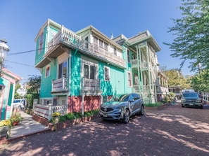 A two-story house with a balcony and a car parked in front.