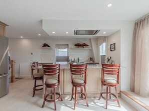 A modern kitchen with a central island, bar stools, and a stainless steel refrigerator. - Jackson St. Penthouse Condo. Middle of Downtown. (Cape May)