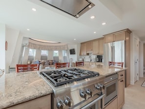 A modern kitchen with a central island, stainless steel appliances, and a dining area with a sofa and chairs.