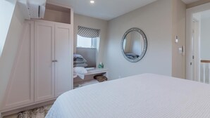 Una camera da letto con un letto, un armadio, uno specchio e una finestra con persiane.