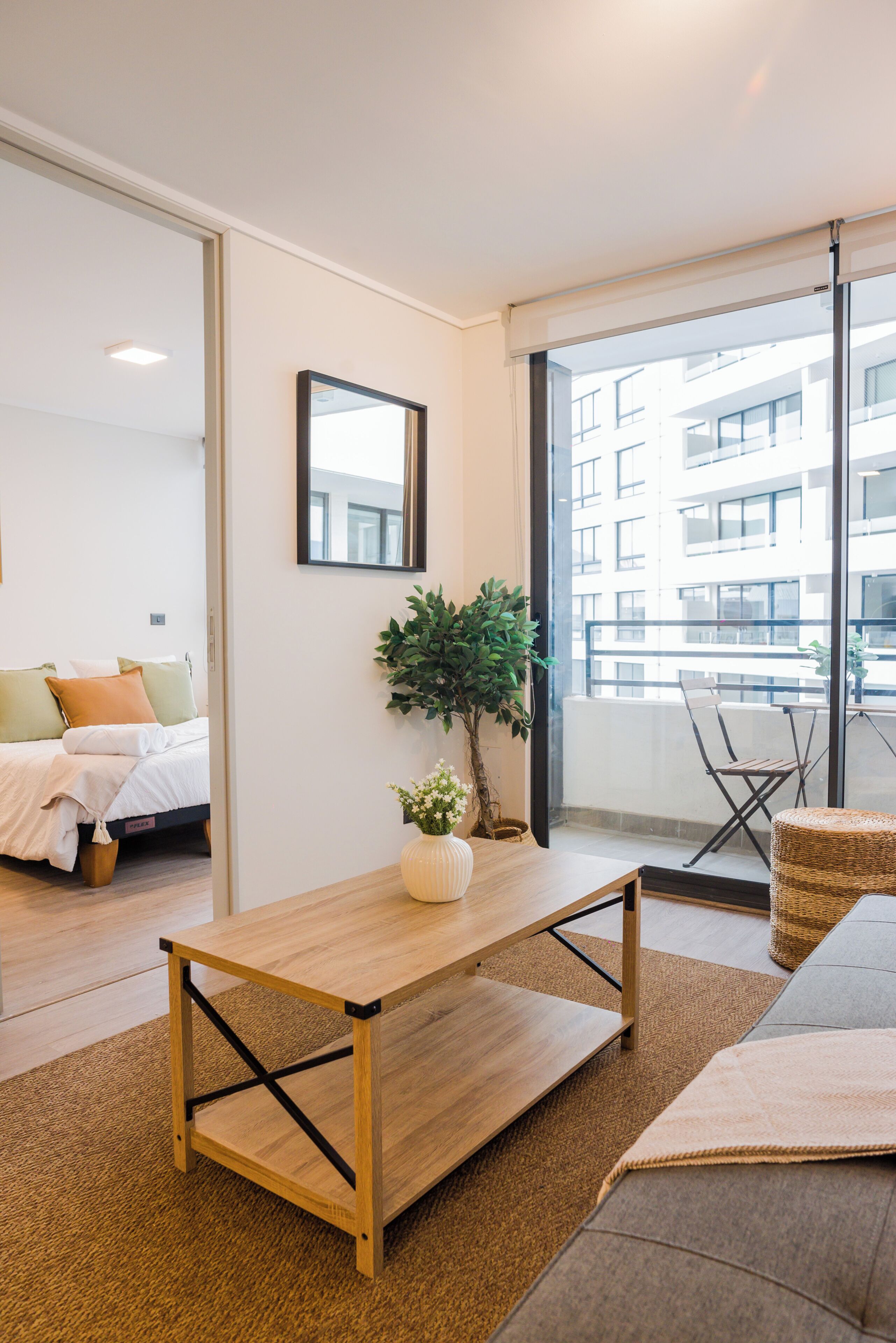 A modern living room with a wooden coffee table, a potted plant, and a sofa.