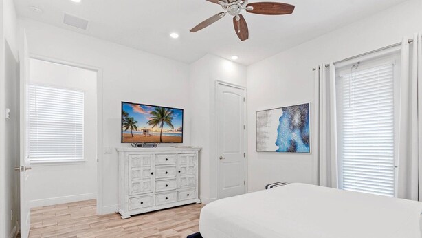 A bedroom with a bed, a dresser, a ceiling fan, and artwork on the walls. - Cozy 2-bedroom house 10 minutes to Disney! (Kissimmee)