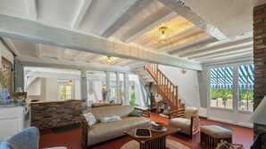 Un vaste espace de vie comprenant un canapé, des fauteuils, une table basse et un escalier menant à un autre niveau.