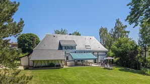 Une maison avec un toit en pente, un patio couvert et une pelouse bien entretenue.