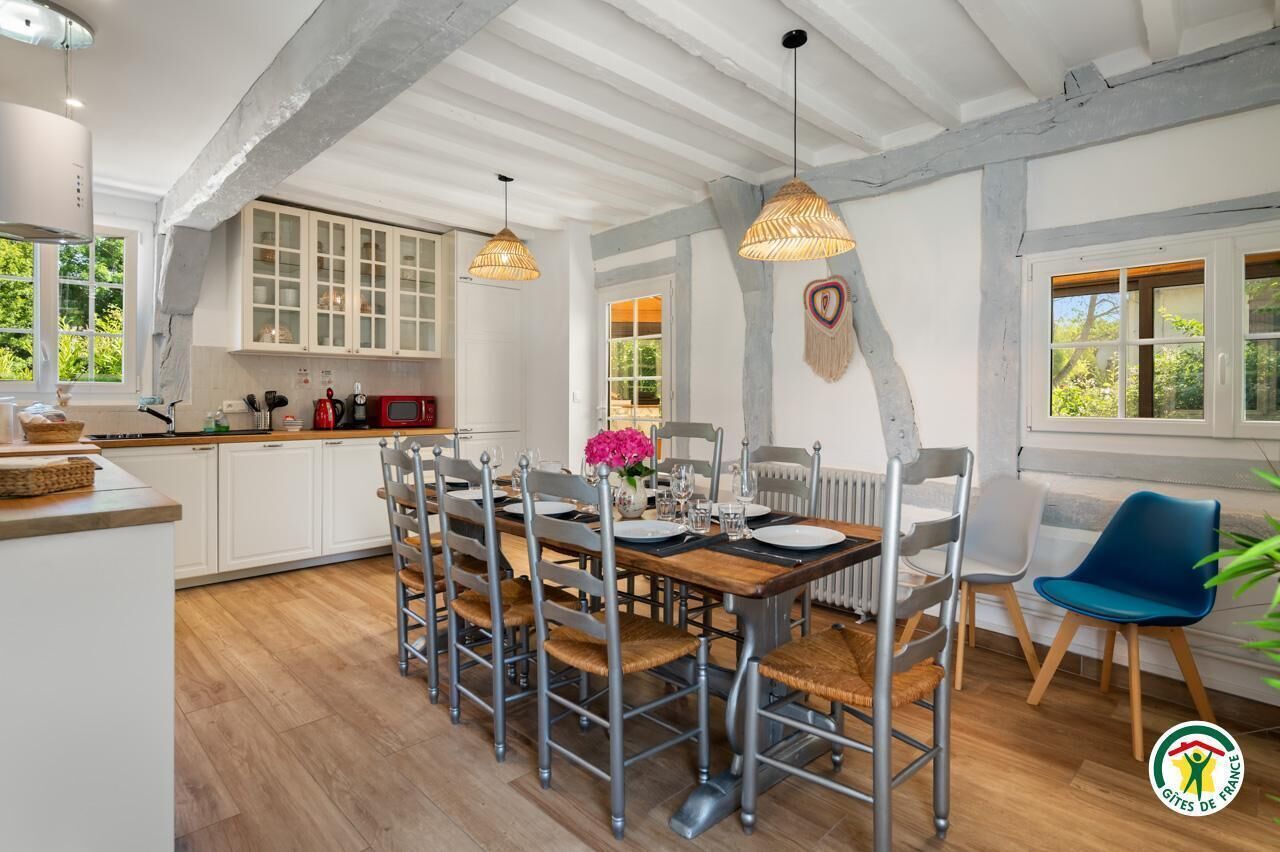 A dining area with a wooden table set for four, surrounded by metal chairs with woven seats.