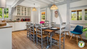 Un coin repas avec une table en bois dressée pour quatre personnes, entourée de chaises en métal dont les assises sont en osier tressé.