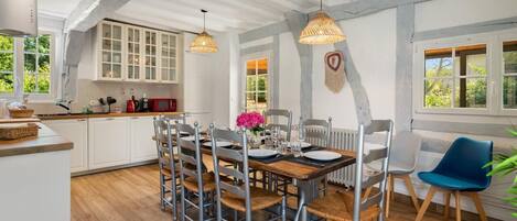 A dining area with a wooden table set for four, surrounded by metal chairs with woven seats.
