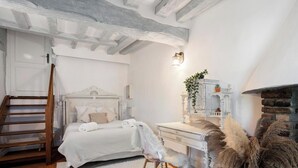 Une chambre à coucher avec un lit, une commode, un miroir, une cheminée et une échelle en bois.