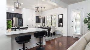 A modern kitchen with a central island, bar stools, and pendant lighting. - Luxury Retreat | Heated Pool•Game Room•Fire Pit (Gilbert)