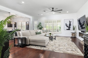 A modern living room with a sectional sofa, a coffee table, and a TV. - Luxury Gilbert + Game Room/Fire Pit*Heated Pool (Gilbert)