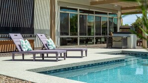 A modern outdoor pool area with lounge chairs and a pergola. - Luxury Retreat | Heated Pool•Game Room•Fire Pit (Gilbert)