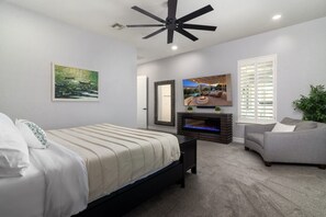 Ein Schlafzimmer mit Bett, Kamin, Fernseher und Deckenventilator.