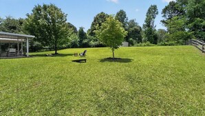 A grassy outdoor area with a covered seating area and a tree.