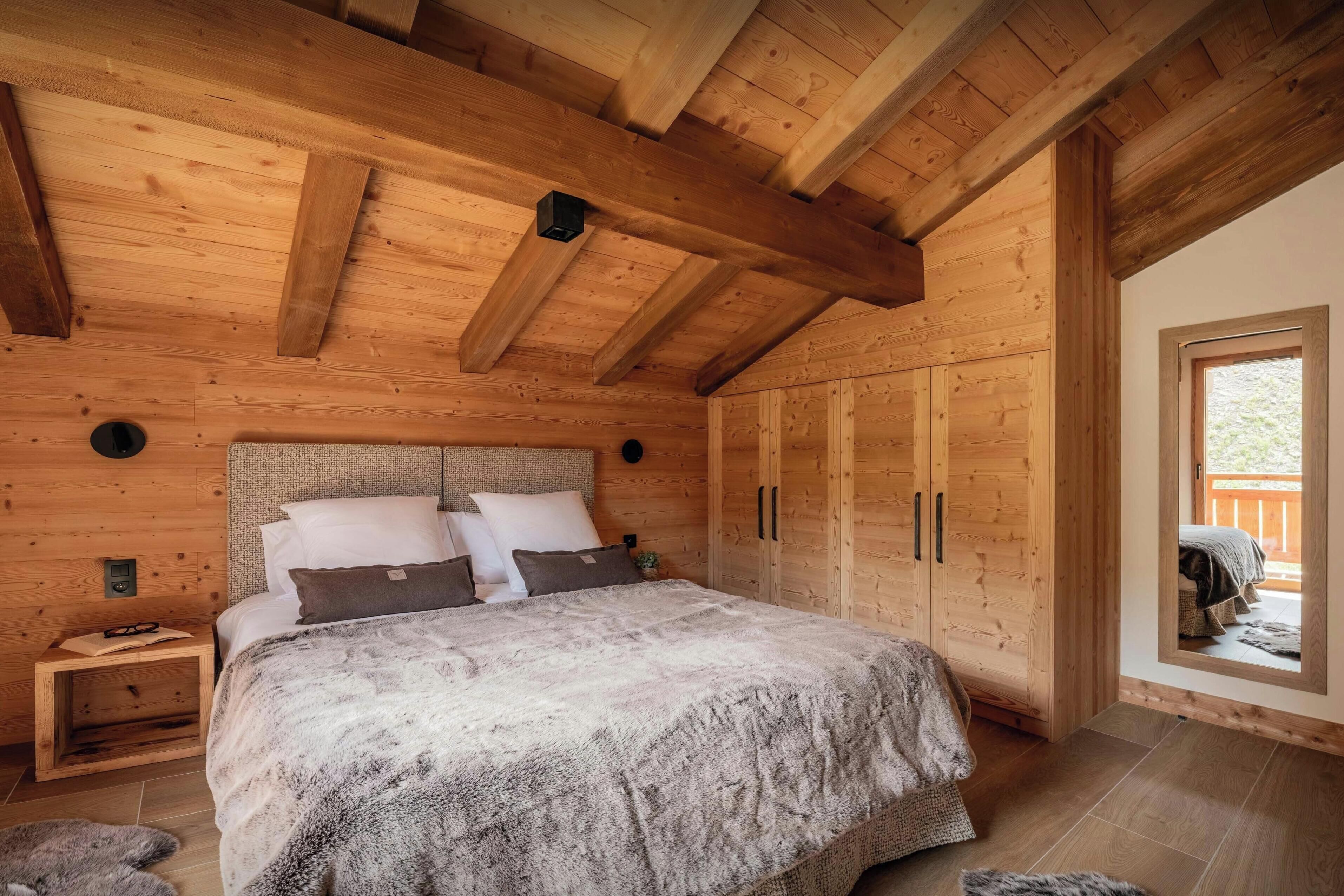 Une chambre à coucher en bois avec un grand lit, une table de chevet et une armoire.