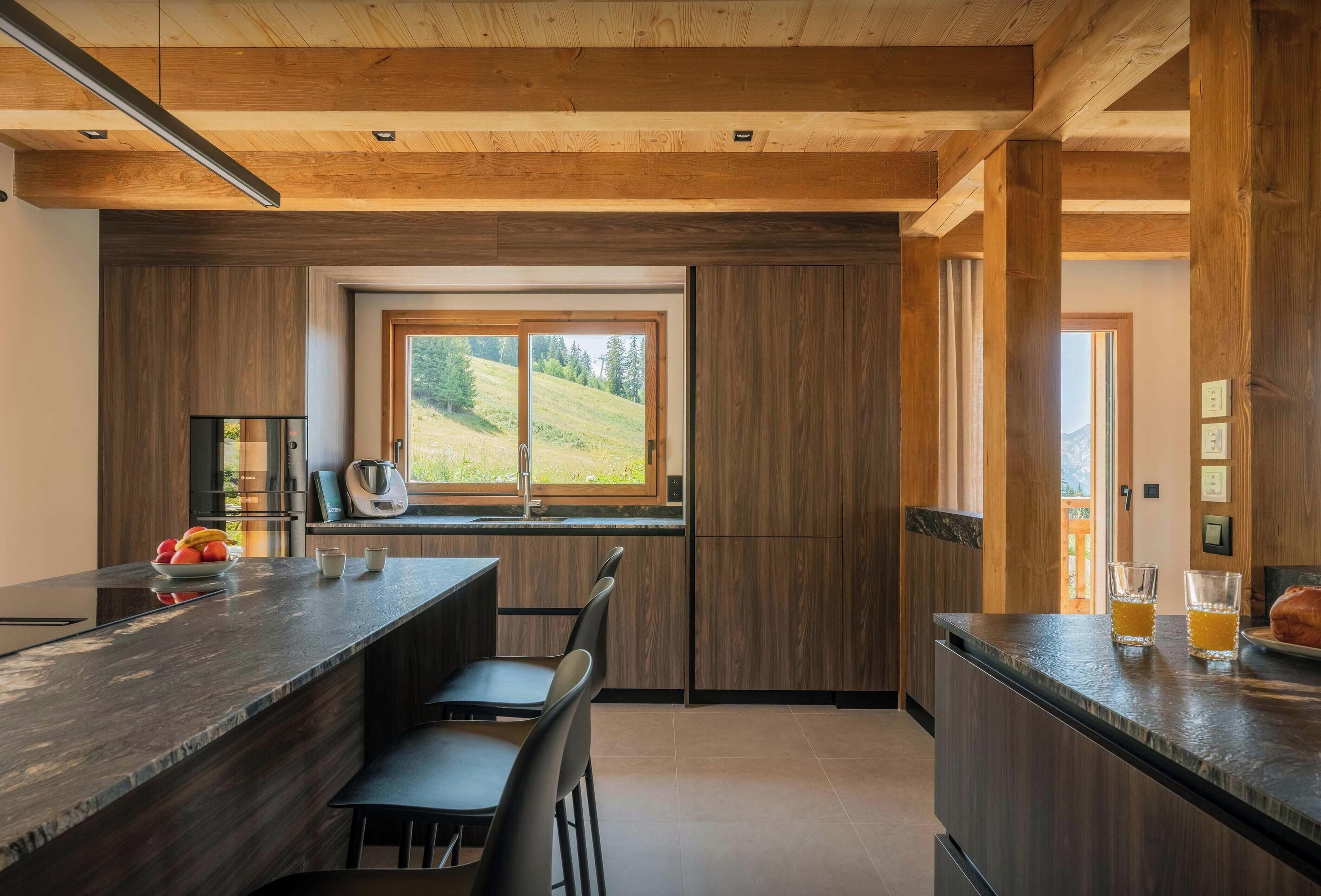 Una cocina moderna con un ventanal grande, vigas de madera y una zona de bar.
