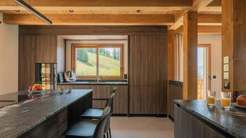 Una cocina moderna con un ventanal grande, vigas de madera y una zona de bar.