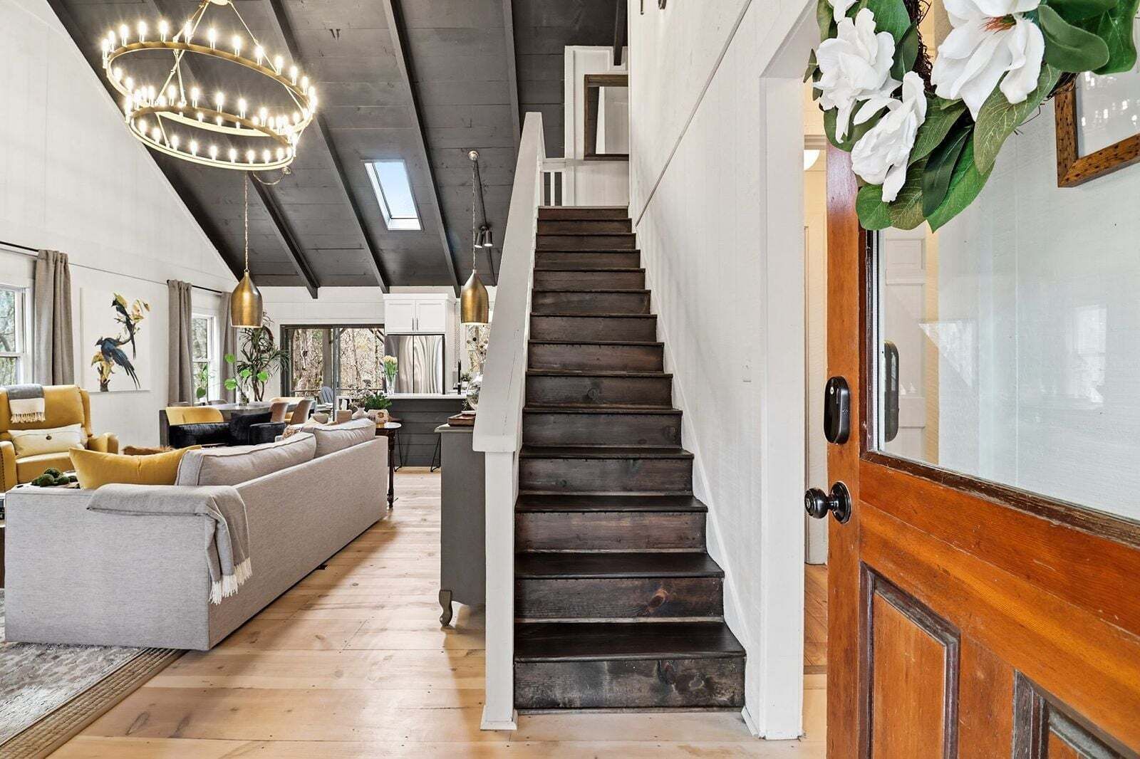 A staircase leading to a second floor, a living area with a sofa and chairs, and a dining area with a table and chairs.