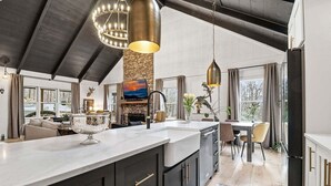 A modern kitchen with a large island, dark cabinetry, and pendant lighting. - Long & Short of It - Pet Friendly, EV Charger, Firepit + Big Canoe Access (Jasper)