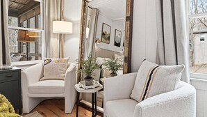 A cozy room with a large mirror, two armchairs, a side table with a plant, and a lamp. - Long & Short of It - Pet Friendly, EV Charger, Firepit + Big Canoe Access (Jasper)