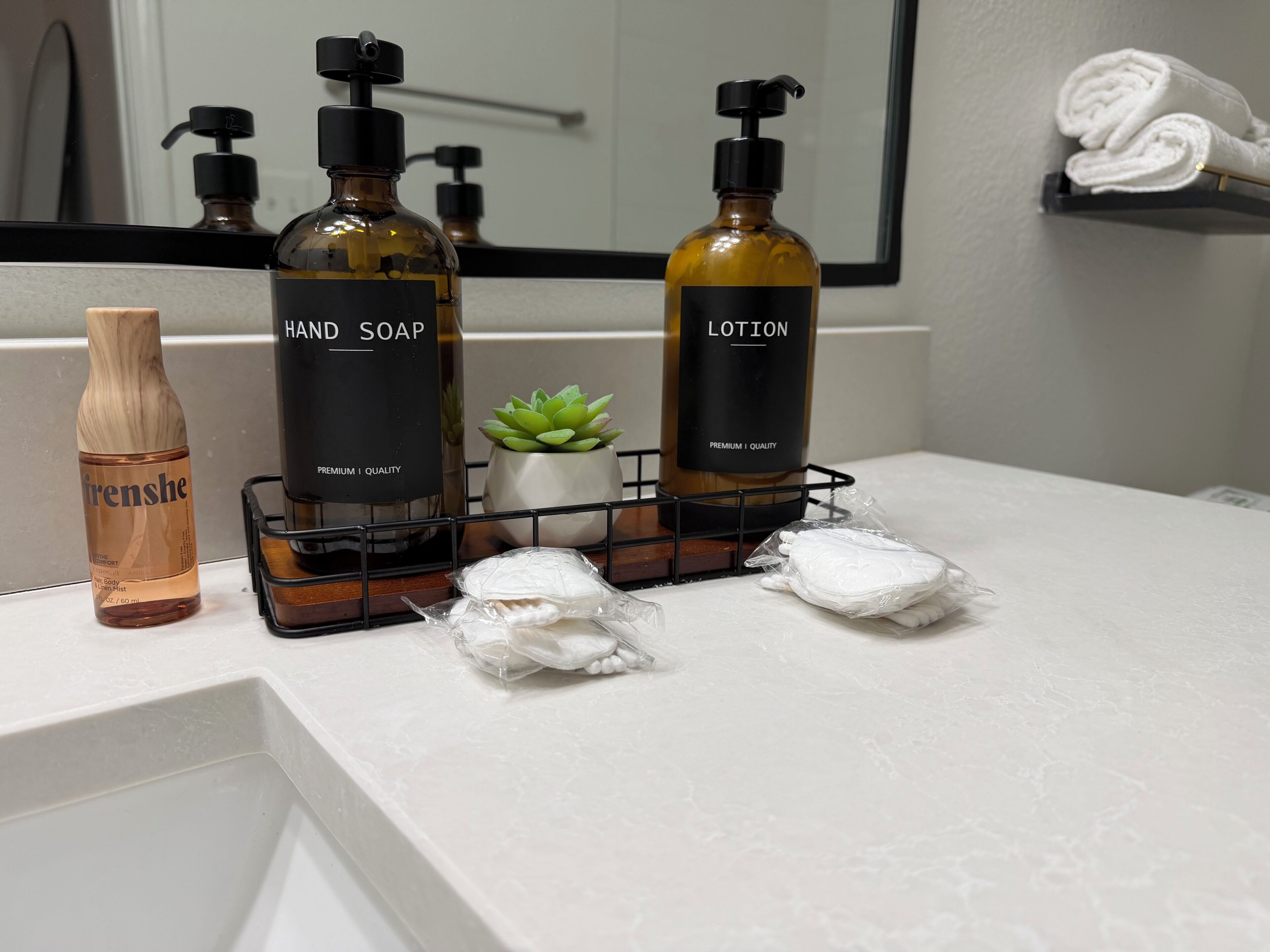 Una encimera de baño con jabón de manos, loción y una botella de madera con la etiqueta 'Frenshe'.