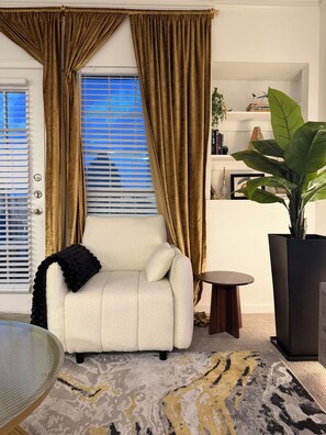 A living room with a white sofa, a round wooden table, a large potted plant, and a patterned rug. - Elegant Atlanta Suite-FREE Parking, Ideal For Long Stays! (Atlanta)