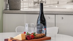 Una cocina con una mesa de comedor dispuesta con comida y vino, una ventana y un lavamanos.