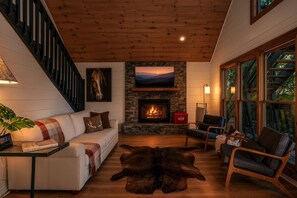 A cozy living room with a fireplace, a sofa, a coffee table, and a leather rug. - Painted Sky Cabin - Long Distance Mountain Views! | Firepit | Pet Friendly (Morganton)