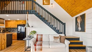 Ein modernes Interieur mit Treppe, einem weißen Sofa, einer Essecke und einer Küche.