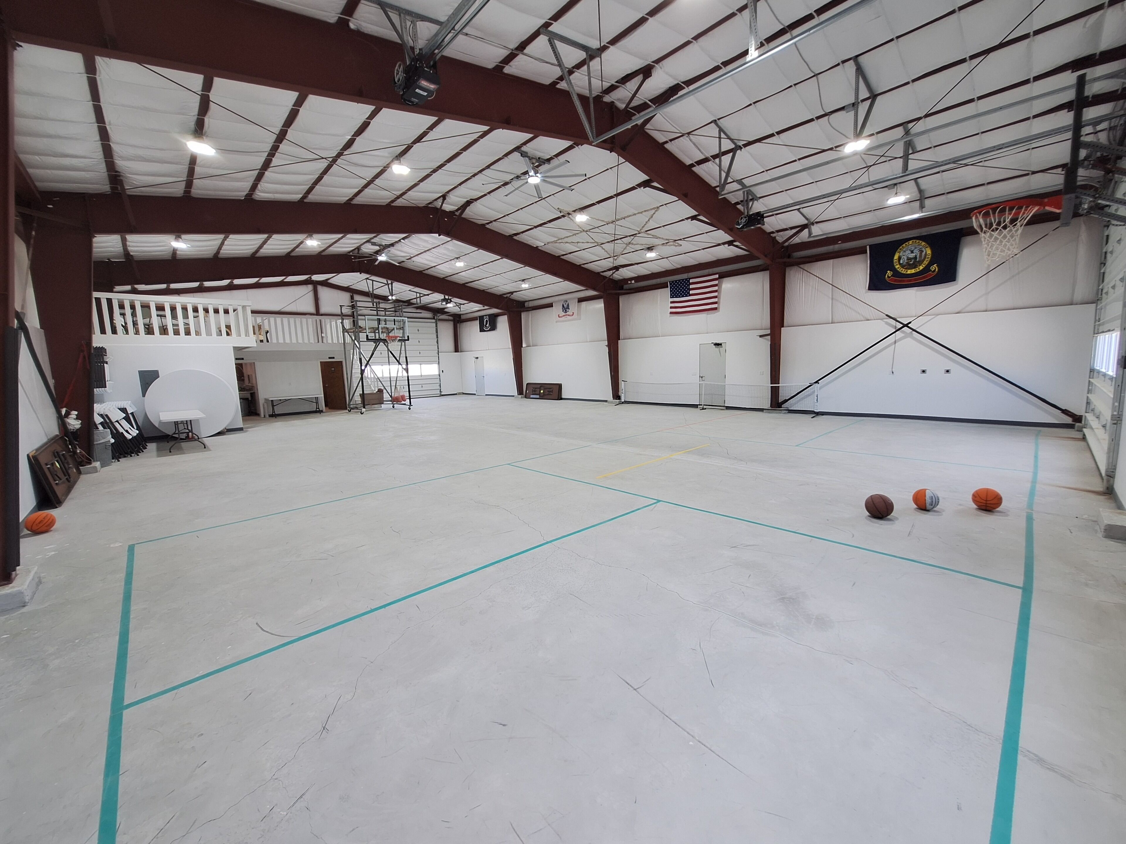 Una cancha de baloncesto interior con techo alto, aros de baloncesto y una bandera.