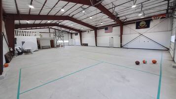 Una cancha de baloncesto interior con techo alto, aros de baloncesto y una bandera.