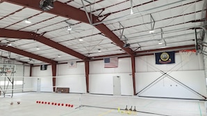 An indoor sports facility with a basketball court, volleyball net, and a flag. - Country Retreat Barndo, great for groups, events, hunting camp & recreation. (Holbrook)