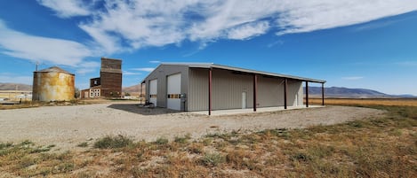 Un bâtiment doté d’un grand garage ouvert et d’une tour à grain, situé dans un cadre rural.
